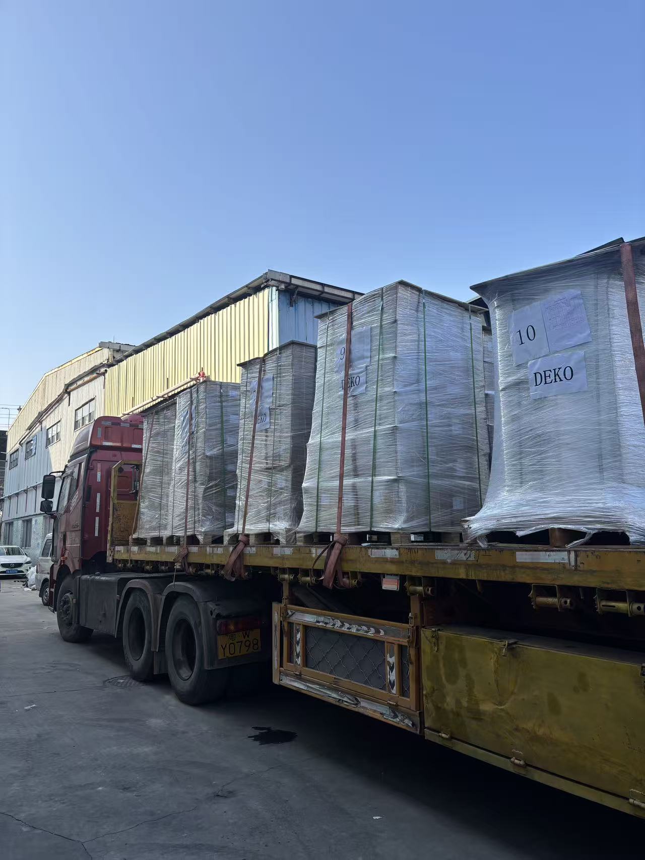 Flatbed truck carrying wrapped pallets of decorative sheet to the port